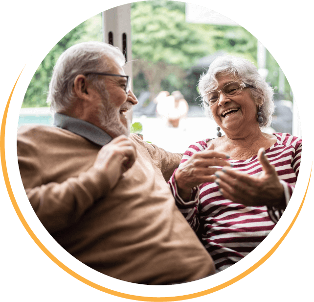 mature couple sitting and laughing with open ear hearing aids in